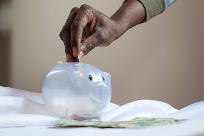 A man deposits a coin in a plastic piggy bank
