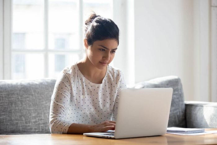 A young woman studies her financial options on her laptop