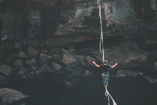 A man walks on a rope across a canyon with a river at the bottom
