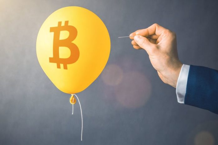 A man demonstrates the risk of cryptocurrency by taking a needle to a yellow balloon with the Bitcoin symbol on it